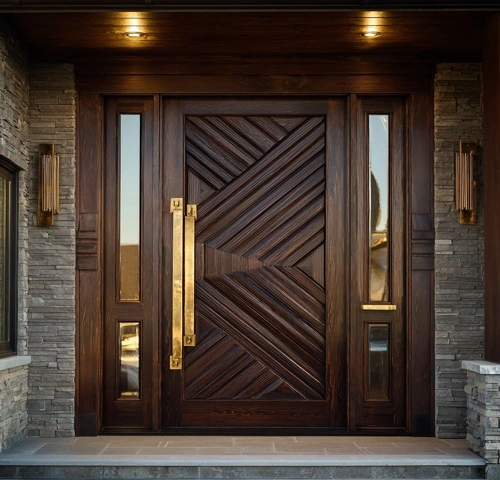 A modern dark wood front door with a geometric chevron pattern, featuring a long vertical brass handle and matching sidelights.