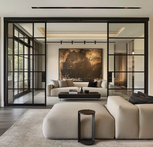 Modern living room with black-framed glass sliding doors separating two minimalist seating areas.